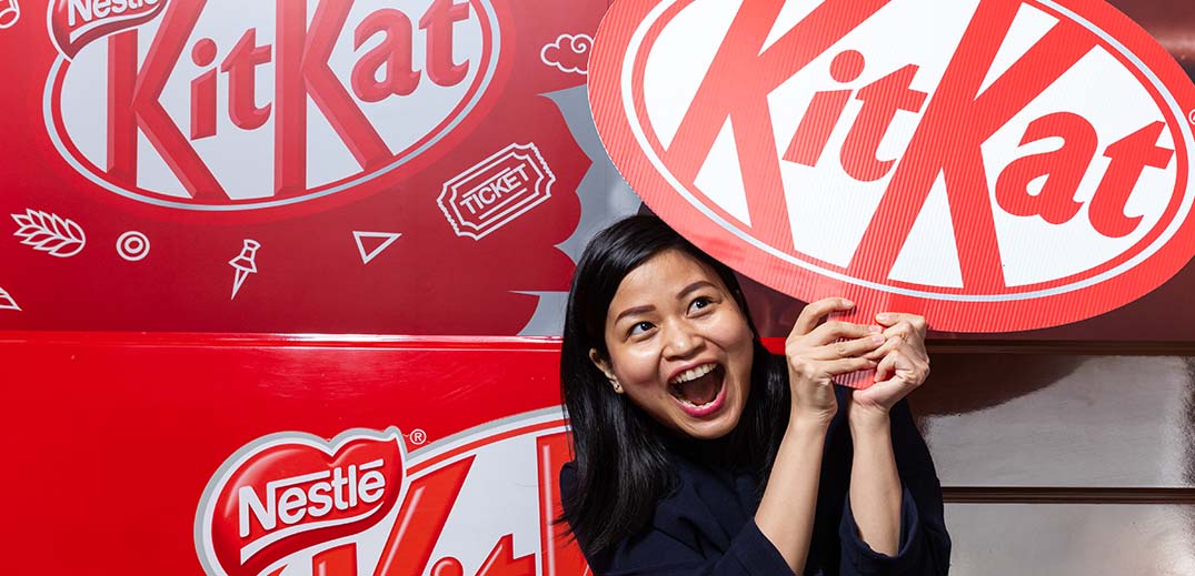 woman holds kitkat sign